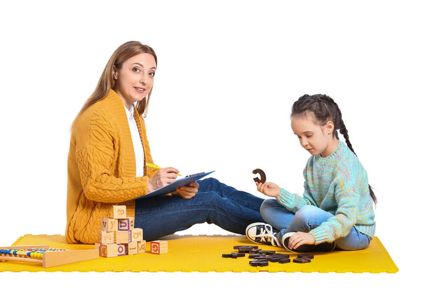 Vrouwelijke psycholoog werken met meisje dat lijdt aan autistische stoornis op witte achtergrond - Foto, afbeelding