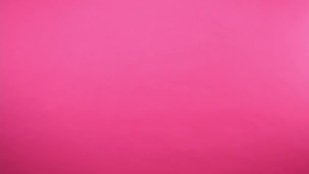 mujer alegre hablando en el teléfono celular mientras pasa por aislado en rosa - Metraje, vídeo
