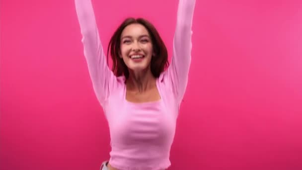 excited woman showing win gesture, jumping and clapping hands isolated on pink - Video, Çekim