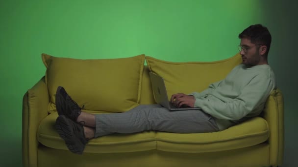 Seitenansicht eines Freiberuflers, der auf dem Sofa sitzt und Laptop auf Grün benutzt - Filmmaterial, Video