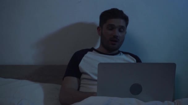 slow motion van jonge man praten en gebaren tijdens videogesprek in bed - Video