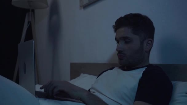 powolny ruch młodego freelancera wpisując na laptopie w sypialni w nocy - Materiał filmowy, wideo