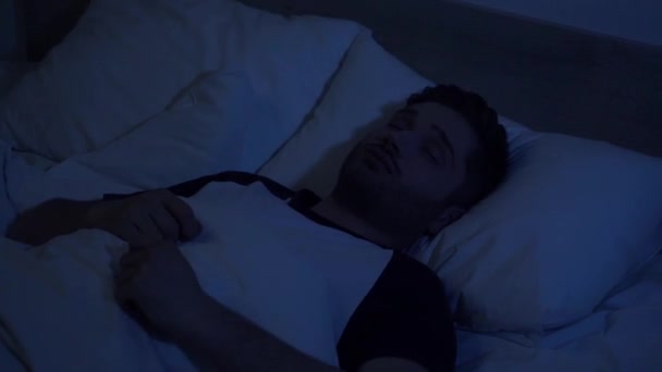 Schläfriger Mann schaltet am frühen Morgen Wecker am Smartphone aus - Filmmaterial, Video