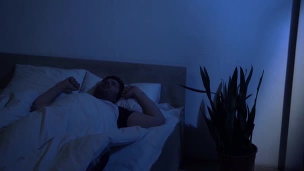 slaperige man geeuwen, stretching en opstaan uit bed in de vroege ochtend - Video