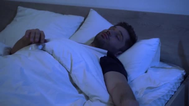 młody człowiek rzucając i obracając się w łóżku w godzinach porannych - Materiał filmowy, wideo