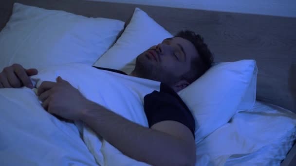 young man sleeping in bed in early morning - Footage, Video