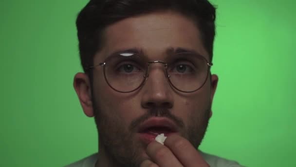 close up vista do homem em óculos comendo pipocas enquanto assiste tv no verde - Filmagem, Vídeo