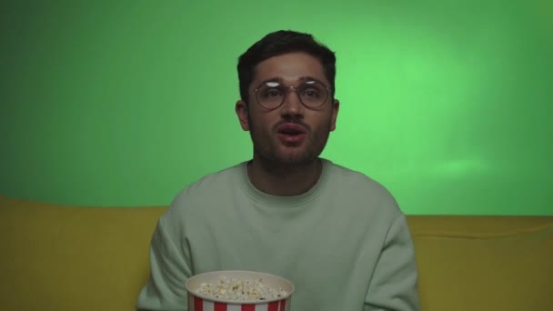 slow motion of man having fun while watching tv and eating popcorn on green - Footage, Video