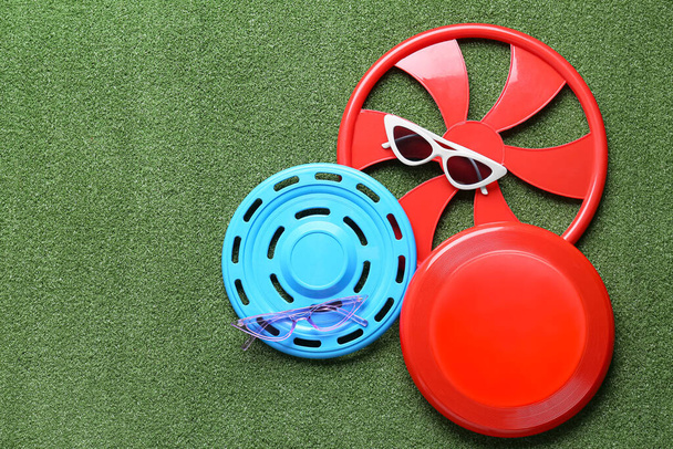 Different frisbee disks and sunglasses on color background - Photo, Image