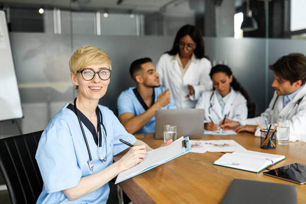 Portrait of young blonde woman doctor having brainstorming with colleagues - Photo, Image