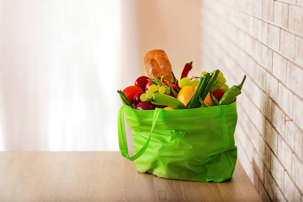 Shopping bag with food on table near brick wall - Fotó, kép