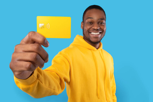 Uomo afroamericano mostra carta di credito su sfondo blu Studio - Foto, immagini