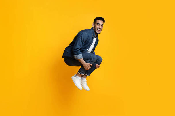 Funny middle-eastern guy fooling on yellow studio background - Foto, immagini