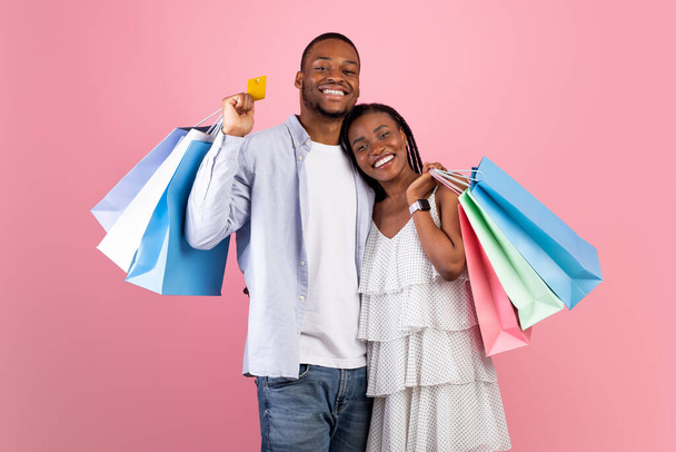 Feliz pareja afro sosteniendo tarjeta de crédito y bolsas - Foto, Imagen