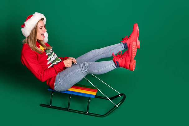 Full body profile photo of funky santa young lady slide wear sweater jeans boots isolated on green background - Photo, Image