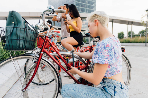 若い白人女性は屋外で南京錠を使用して自転車を締結 - 写真・画像