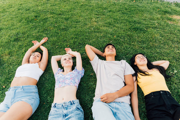 Grupo de jóvenes amigos multiétnicos al aire libre yaciendo hierba sonriendo sentirse libre y relajante - banner copyspace publicidad - Foto, imagen