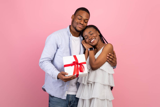 Ευτυχισμένος μαύρος άνδρας που κάνει έκπληξη για γυναίκα που δίνει κουτί - Φωτογραφία, εικόνα