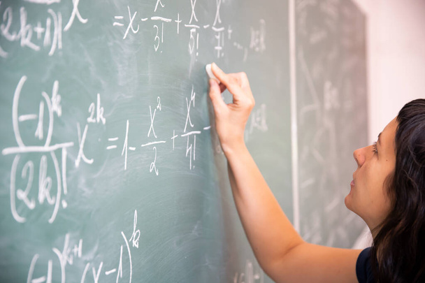 Teacher or student writing on blackboard during math lesson in school classroom. - Foto, afbeelding
