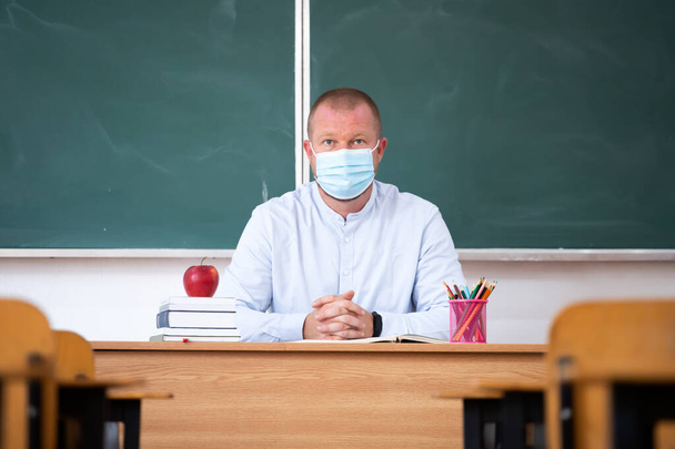  Teacher with mask in the classroom. Social distanting and classroom safety during coronavirus epidemic - Photo, image