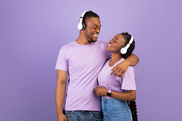 Portrét černošky pár v sluchátkách objímání ve studiu - Fotografie, Obrázek