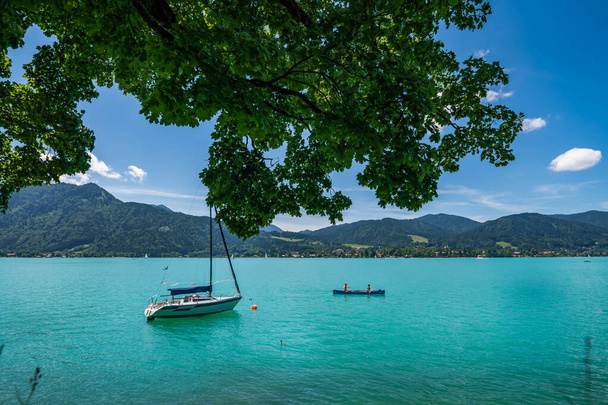 Turquiose Tegernsee. Popularne jezioro w samym sercu Bawarii z pięknym zielonym niebieskawym kolorem wody w lecie z łodzi i dwóch kajakarzy ludzi. - Zdjęcie, obraz