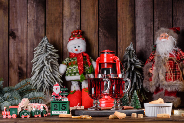 Karácsonyi forralt vörösbor fűszerekkel és gyümölcsökkel egy sötét asztalon. Hagyományos forró ital karácsonykor - Fotó, kép