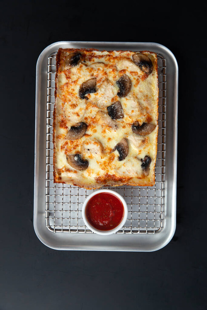 Detroit pizza op een ijzeren dienblad met saus op een donkere achtergrond. selectieve focus. - Foto, afbeelding