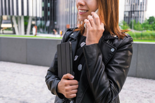 Mujer de negocios moderna hablando en el teléfono inteligente cerca del centro de negocios - Foto, imagen