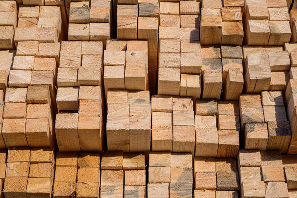 Piles of wooden planks at the sawmill for the manufacture of cladding. Warehouse of boards in the open air for the construction of houses. Timber in stacks, construction materials industry. - Foto, afbeelding