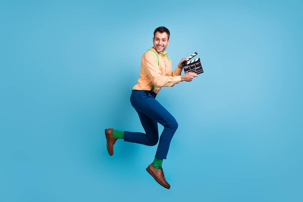 Kuva hauska tuottaja kaveri hypätä pidä liitutaulu ajaa kulumista henkselit paita eristetty sininen väri tausta - Valokuva, kuva