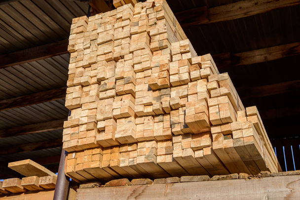 Piles of wooden planks at the sawmill for the manufacture of cladding. Warehouse of boards in the open air for the construction of houses. Timber in stacks, construction materials industry. - Photo, Image