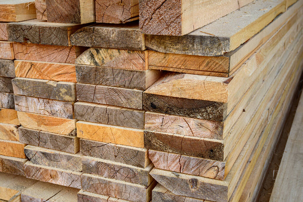 Piles of wooden planks at the sawmill for the manufacture of cladding. Warehouse of boards in the open air for the construction of houses. Timber in stacks, construction materials industry. - Foto, Imagen