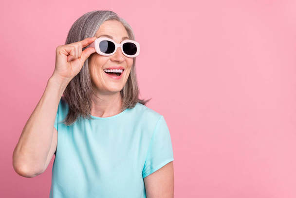 Photo of nice aged white hair lady look empty space wear spectacles teal blouse isolated on pink color background - Fotó, kép