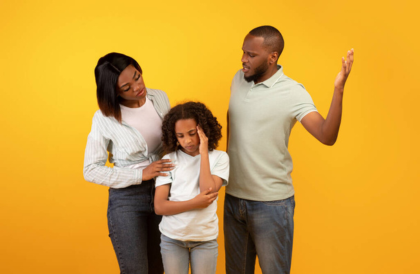 Młody czarny ojciec krzyczy na córkę i matkę pocieszając zdenerwowaną małą dziewczynkę, przytulając ją i pocieszając - Zdjęcie, obraz