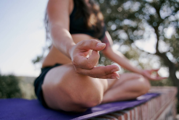 Close-up hand of a woman doing yoda outdoors. Woman doing meditation exercise in the background of nature, select focus. - 写真・画像