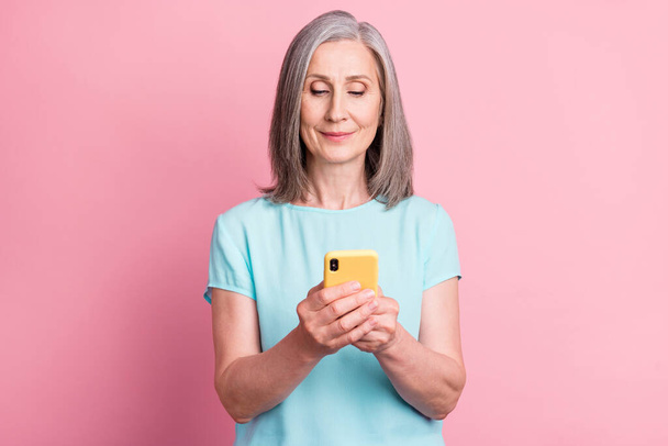 Photo of nice elder grey hairdo lady look telephone wear teal blouse isolated on pink color background - Fotografie, Obrázek
