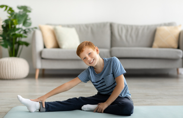 Bambino carino che si estende sul tappeto fitness a casa - Foto, immagini