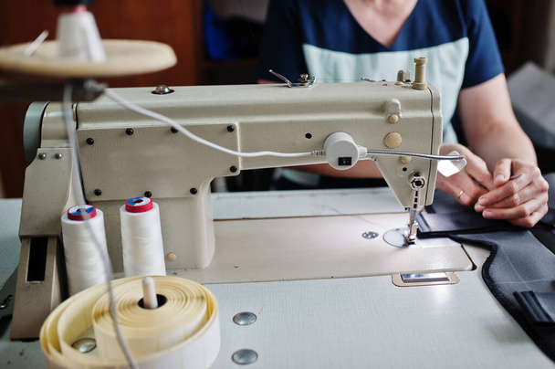 Female hands stitching fabric on professional manufacturing machine at workplace. Sewing process. - Foto, Bild