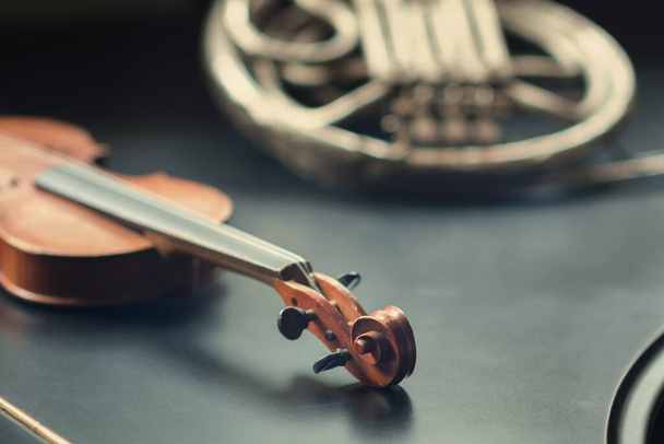 Detail einer Geige und verschwommenem Waldhorn auf dem schwarzen Flügel, selektiver Fokus - Foto, Bild