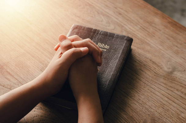 tyttö istuu ja rukoilee siunauksia Jumalalta Raamatun taitettu kädet Raamatun, hengellinen ja uskonnollinen rukous, kommunikoida, puhua Jumalalle. rakkaus ja anteeksianto - Valokuva, kuva