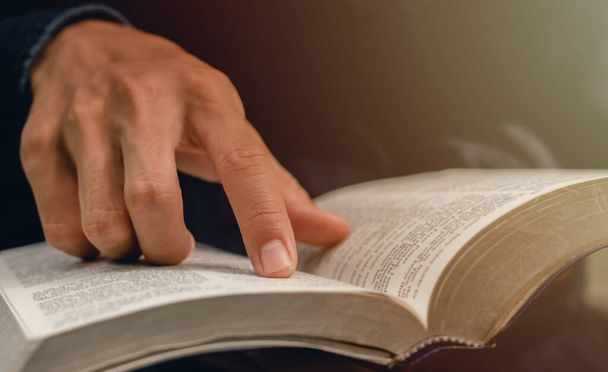 junger Mann zeigt auf ein Bibelthema und liest sonntags in der Bibel, um Gottes Segen zu empfangen. - Foto, Bild