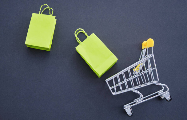 mini shopping cart, eco-friendly paper bag for shopping in hypermarkets on a black background. - Fotó, kép
