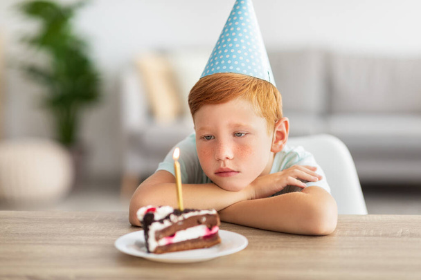 bouleversé anniversaire garçon regarder couvercle bougie sur son gâteau - Photo, image