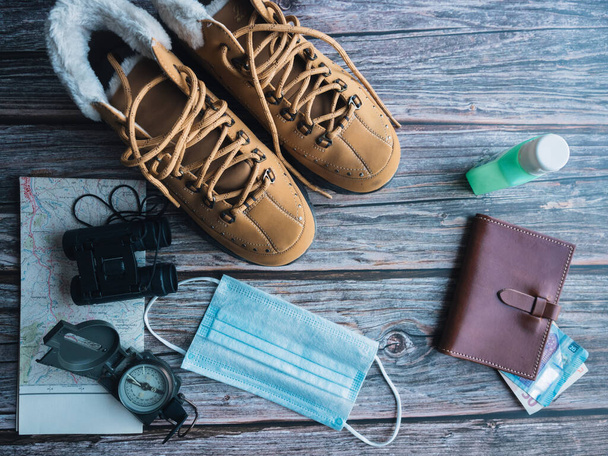 Concept de voyage, bottes, jumelles, boussole, portefeuille, masque, argent, gel hydro-alcoolique - Photo, image