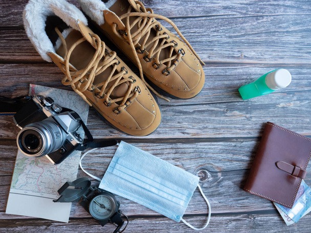 Ταξιδιωτική ιδέα, μπότες, φωτογραφική μηχανή, πυξίδα, πορτοφόλι, μάσκα, χρήματα, υδροαλκοολικός τζελ, - Φωτογραφία, εικόνα