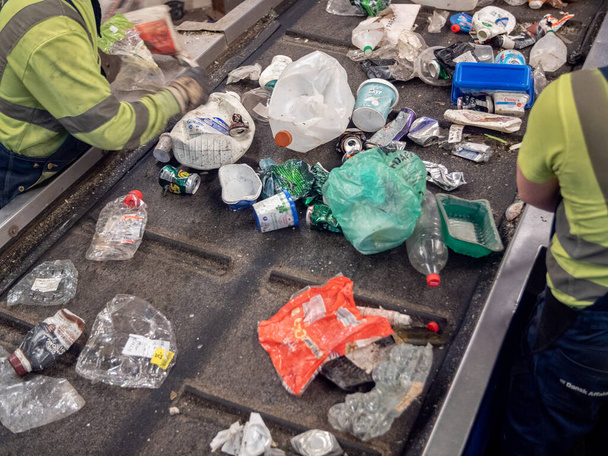 Mensen die in een afvalverwerkingsinstallatie aan een transportband werken - Foto, afbeelding