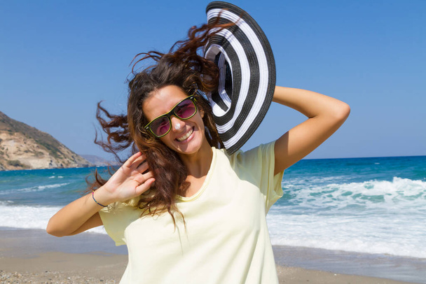 Молодая женщина наслаждается солнцем на пляже с солнцезащитным кремом - Фото, изображение