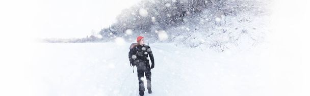 Ein Mann ist mit einem Rucksack unterwegs. Winterwanderung im Wald. Touristin bei einem Winterspaziergang im Park. - Foto, Bild