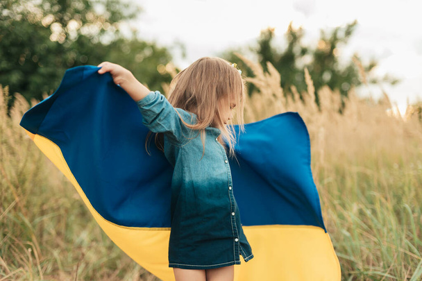 Ukraines Independence Flag Day. Constitution day. Ukrainian child girl in embroidered shirt vyshyvanka with yellow and blue flag of Ukraine in field. flag symbols of Ukraine. Kyiv, Kiev day - Photo, image